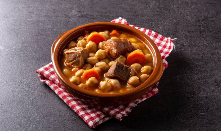 Traditional Spanish cocido madrileño in bowl on black background